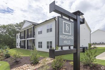 A sign for highland hills stands in front of a building.